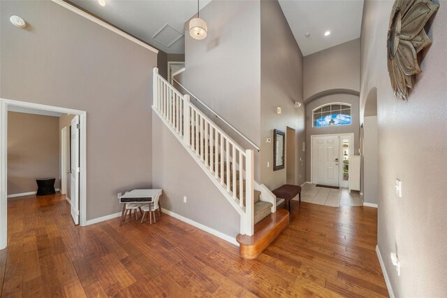 1048 Lake Berkley Dr, Kissimmee, FL 34746 - foyer entrance with baseboards, arched walkways, hardwood / wood-style flooring, a towering ceiling, and stairs