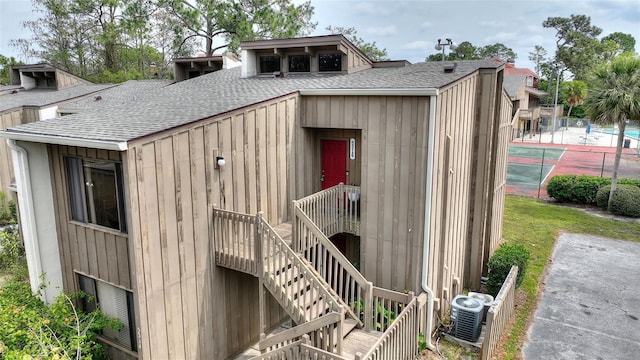 exterior space with central air condition unit, a shingled roof, and board and batten siding