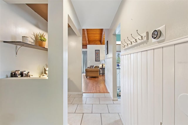 corridor with lofted ceiling with beams, wood ceiling, and light tile patterned floors