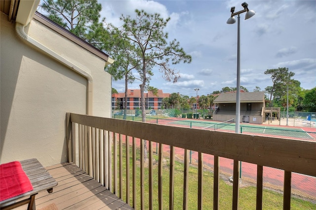 wooden deck featuring a tennis court and fence