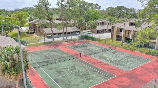 view of tennis court with a residential view and fence