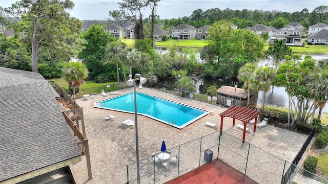 community pool with a water view, fence, and a residential view