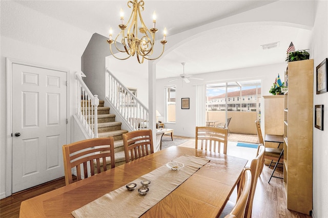 1149 S Beach Cir, Kissimmee, FL 34746 - dining space featuring visible vents, arched walkways, ceiling fan with notable chandelier, wood finished floors, and stairs