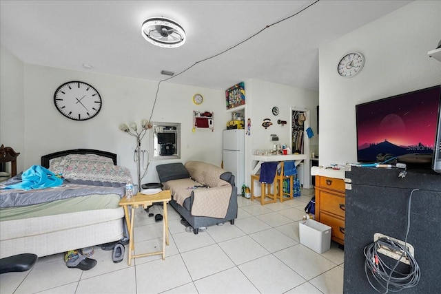 bedroom with freestanding refrigerator and light tile patterned flooring