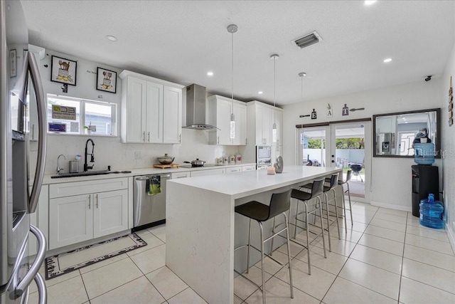 kitchen with a center island, a sink, wall chimney range hood, a breakfast bar, and stainless steel appliances