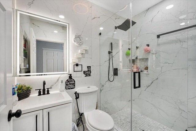 bathroom featuring toilet, a marble finish shower, and vanity