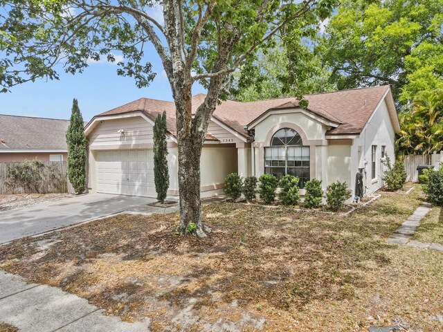 1345 Tindaro Dr, Apopka, FL 32703 - view of front of house featuring roof with shingles, concrete driveway, stucco siding, fence, and a garage