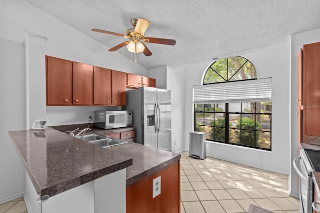 1345 Tindaro Dr, Apopka, FL 32703 - kitchen featuring lofted ceiling, stainless steel appliances, a sink, dark countertops, and a peninsula