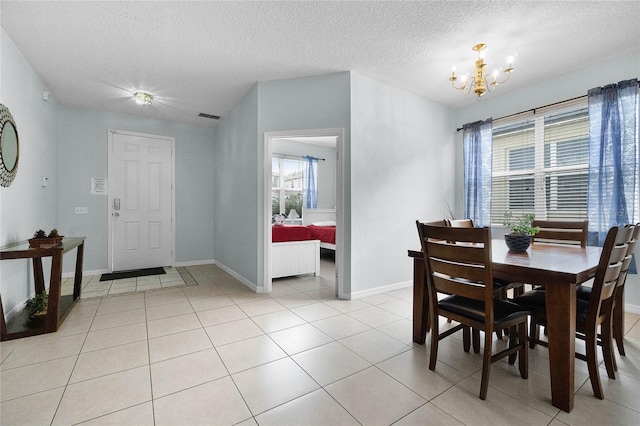 dining space with light tile patterned flooring, a textured ceiling, visible vents, a chandelier, and baseboards