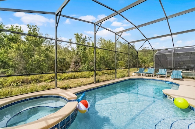 view of swimming pool featuring glass enclosure, a pool with connected hot tub, and a patio