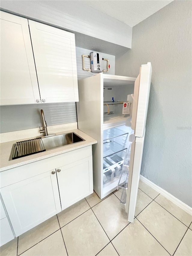 403 Terry St, Wildwood, FL 34785 - kitchen featuring white cabinets, light countertops, baseboards, a sink, and light tile patterned floors
