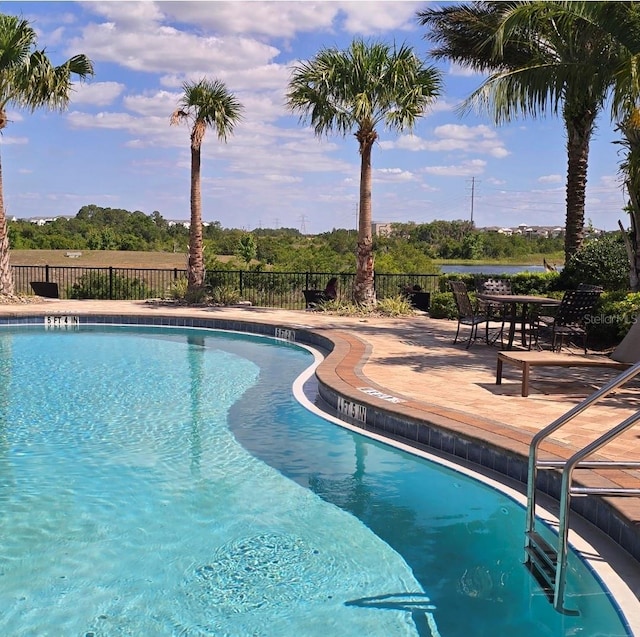 community pool with a patio area and fence
