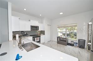 1237 Tallow Rd Unit 1237, Apopka, FL 32703 - kitchen featuring light countertops, a sink, white cabinetry, appliances with stainless steel finishes, and marble finish floor
