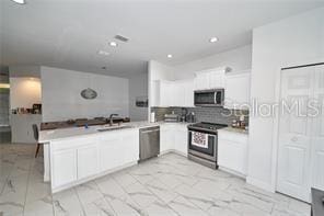 1237 Tallow Rd Unit 1237, Apopka, FL 32703 - kitchen with marble finish floor, white cabinetry, a peninsula, and appliances with stainless steel finishes