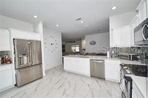 1237 Tallow Rd Unit 1237, Apopka, FL 32703 - kitchen featuring white cabinets, a peninsula, stainless steel appliances, and tasteful backsplash