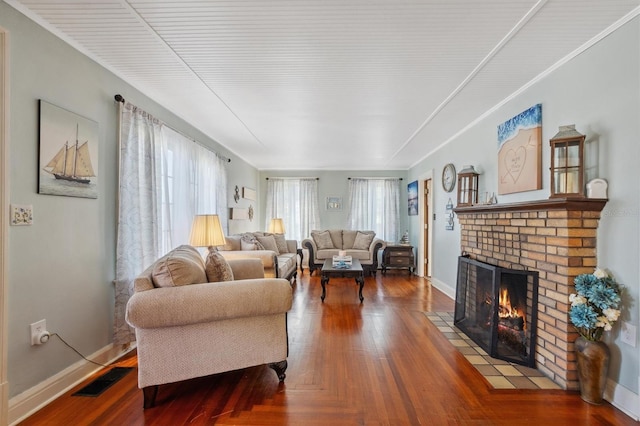 living room featuring baseboards, a fireplace, visible vents, and wood finished floors