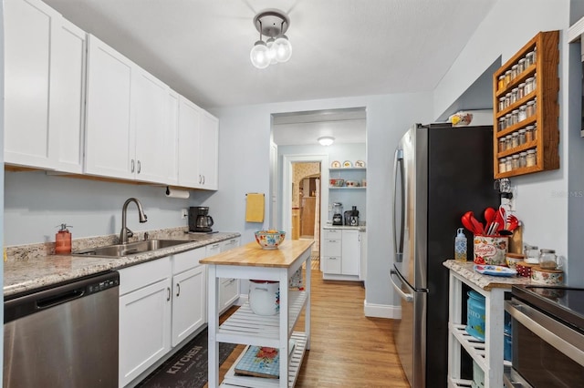 kitchen featuring white cabinets, a sink, stainless steel appliances, and light wood-type flooring
