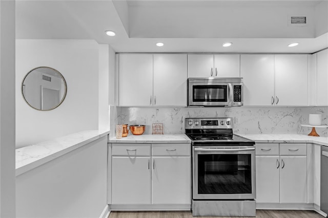 5600 Collins Ave Unit 6P, Miami Beach, FL 33140 - kitchen featuring stainless steel appliances, light stone counters, white cabinetry, and recessed lighting