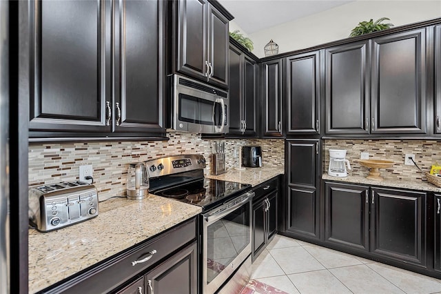 510 Captiva Dr, Davenport, FL 33896 - kitchen with light tile patterned floors, stainless steel appliances, backsplash, light stone countertops, and dark cabinets