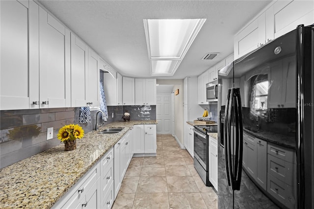 kitchen featuring backsplash, a sink, stainless steel appliances, visible vents, and white cabinets