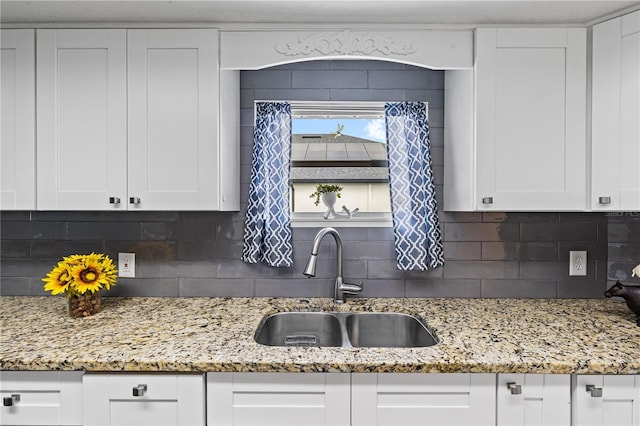 kitchen featuring white cabinetry, a sink, and light stone counters