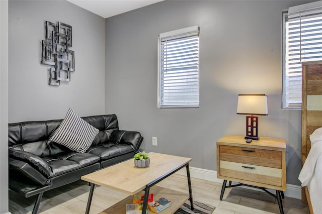living area featuring light wood-style flooring, baseboards, and a healthy amount of sunlight