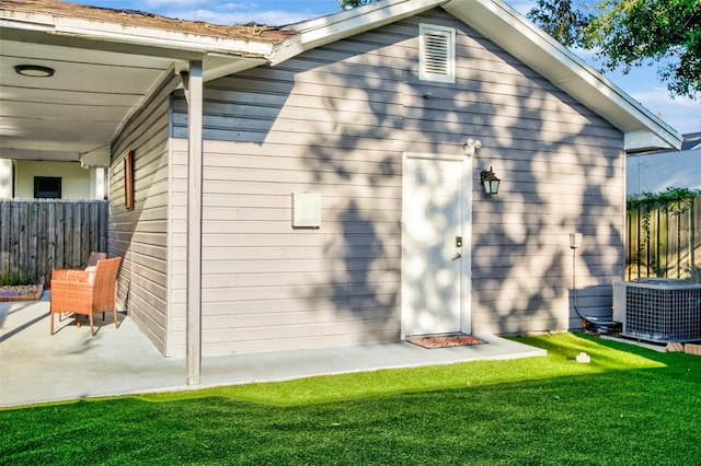 exterior space with a patio area, a lawn, cooling unit, and fence