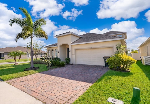 view of front of house with stucco siding, a garage, a front lawn, and decorative driveway
