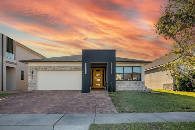 2566 Trielle Ave, Kissimmee, FL 34741 - view of front of property with stone siding, stucco siding, a front lawn, decorative driveway, and a garage