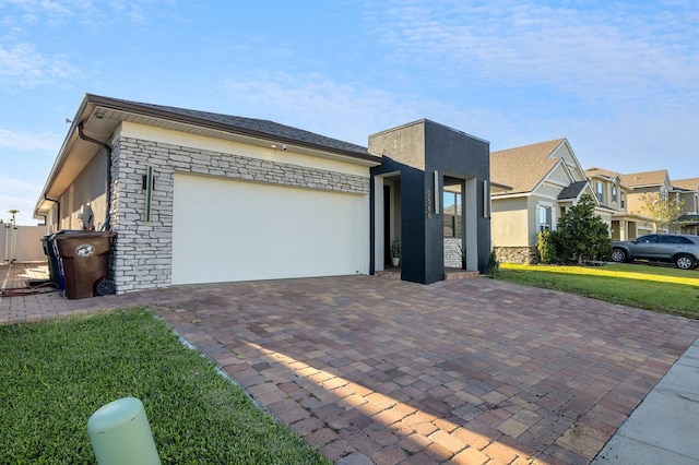 2566 Trielle Ave, Kissimmee, FL 34741 - view of front of home featuring stucco siding, an attached garage, stone siding, decorative driveway, and a front yard