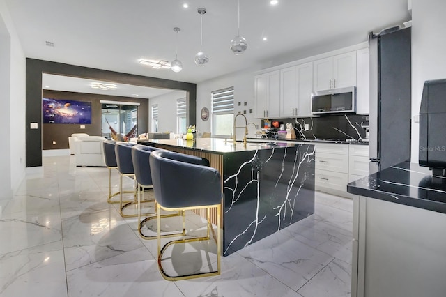 2566 Trielle Ave, Kissimmee, FL 34741 - kitchen with stainless steel microwave, backsplash, marble finish floor, a sink, and white cabinets