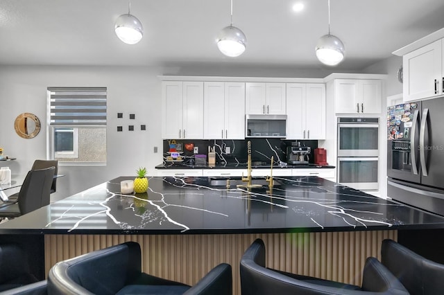 2566 Trielle Ave, Kissimmee, FL 34741 - kitchen with white cabinets, refrigerator with ice dispenser, stainless steel double oven, tasteful backsplash, and a kitchen breakfast bar