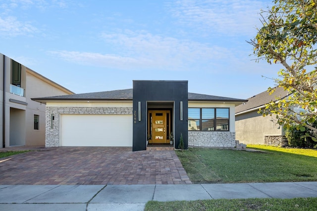 2566 Trielle Ave, Kissimmee, FL 34741 - view of front of property with stucco siding, an attached garage, stone siding, decorative driveway, and a front lawn