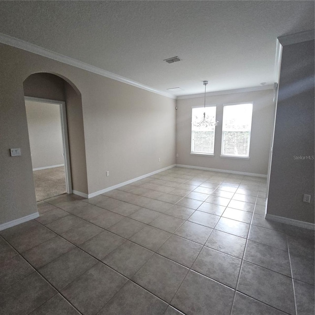 tiled empty room featuring crown molding, an inviting chandelier, baseboards, arched walkways, and visible vents