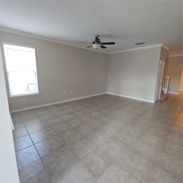 spare room featuring light tile patterned floors, ornamental molding, baseboards, and ceiling fan