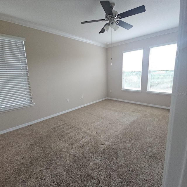 carpeted empty room with baseboards, ornamental molding, and a ceiling fan