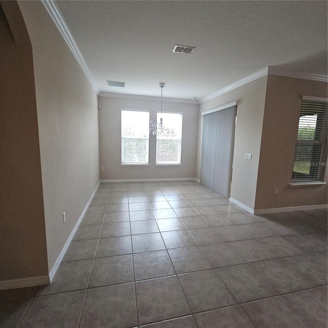 tiled empty room with baseboards, visible vents, a notable chandelier, and ornamental molding