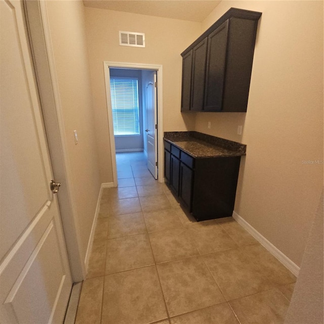 hallway with light tile patterned flooring, baseboards, and visible vents