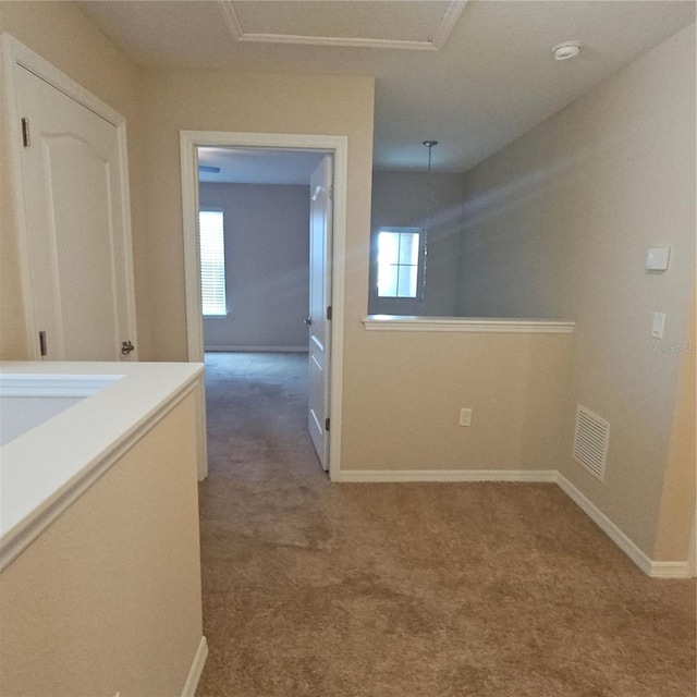 hall with baseboards, visible vents, and carpet floors