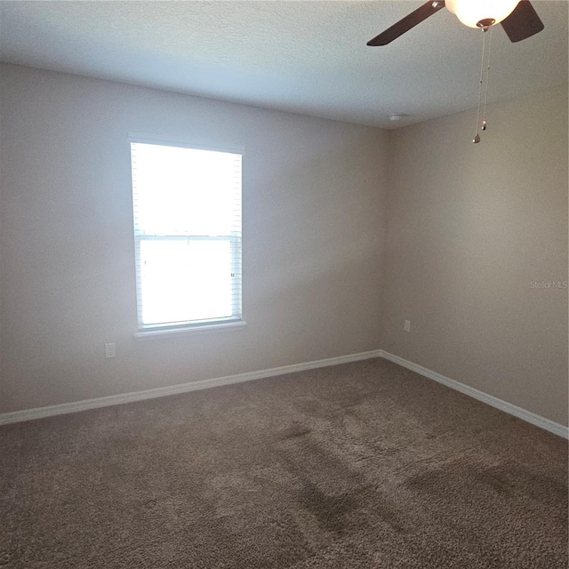 spare room with baseboards, carpet floors, ceiling fan, and a textured ceiling