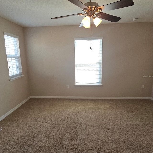 spare room with a ceiling fan, plenty of natural light, and carpet