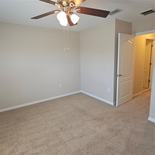spare room with light carpet, baseboards, visible vents, and ceiling fan