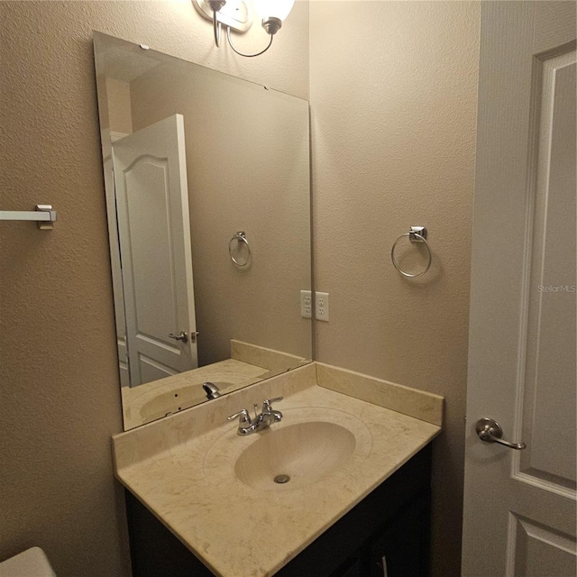 bathroom with a textured wall and vanity