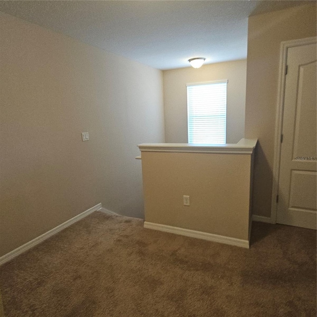 carpeted empty room featuring baseboards
