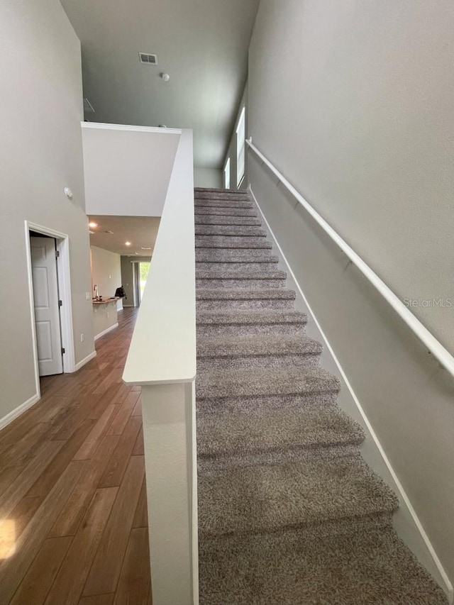 5273 Sanders Oak Trl, Saint Cloud, FL 34771 - stairway featuring visible vents, baseboards, a high ceiling, and wood finished floors
