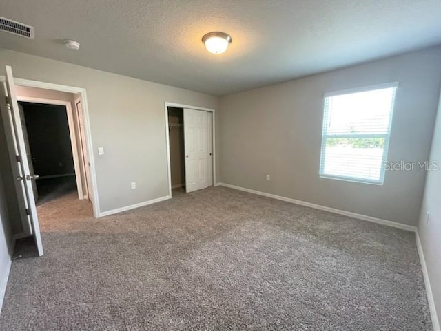 5273 Sanders Oak Trl, Saint Cloud, FL 34771 - unfurnished bedroom featuring a textured ceiling, a closet, baseboards, and carpet floors