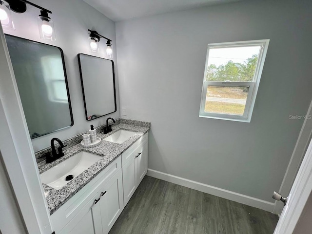 bathroom with double vanity, a sink, baseboards, and wood finished floors