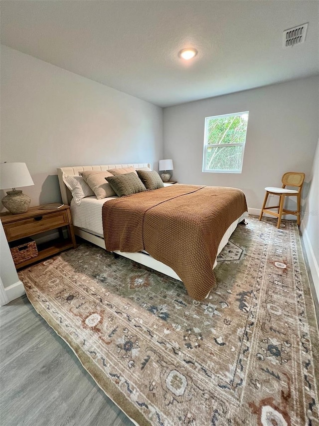 bedroom featuring baseboards, visible vents, and wood finished floors