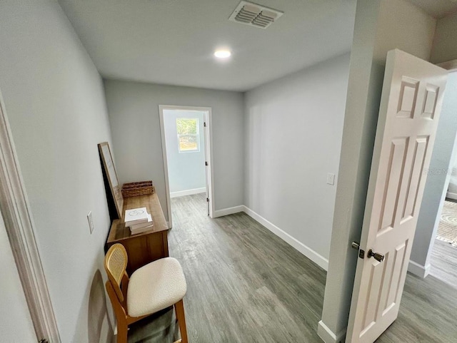 hall with baseboards, visible vents, and wood finished floors