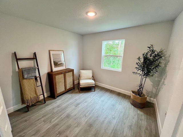 living area with baseboards and wood finished floors